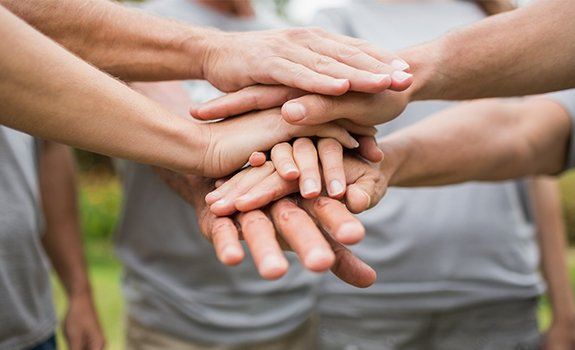 People in a circle with their hands together in the center