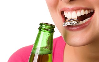 Woman opening a bottle with her teeth
