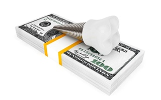Model implant and money stack representing cost of dental implants in Rockwall