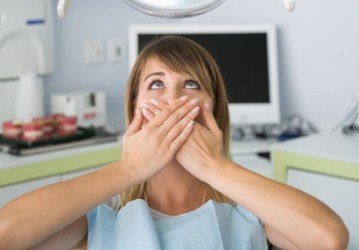 Fearful woman in need of sedation dentistry covering mouth