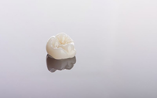 Tooth-colored crown isolated on reflective surface