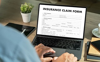 Person filling out insurance claim form on their laptop