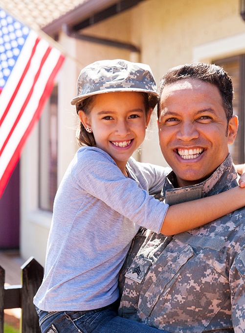 Smiling veteran holding his daughter