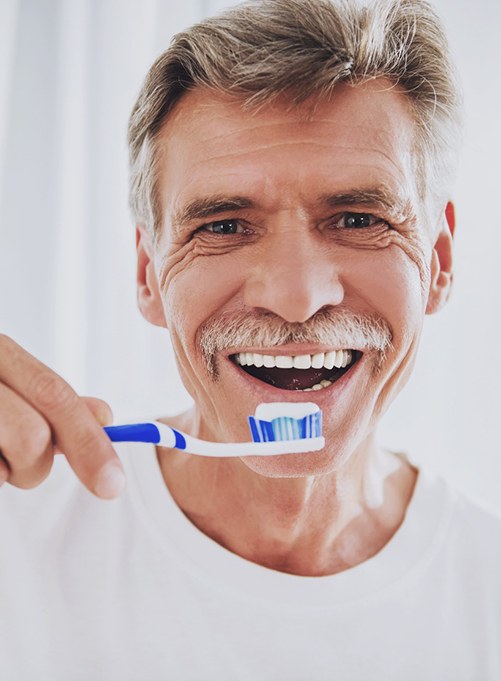 Man smiling and holding a toothbrush