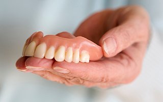 Hand holding dentures in Rockwall, TX