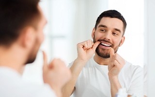 Man smiling while flossing teeth