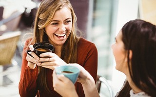 Two friends smiling while drinking coffee